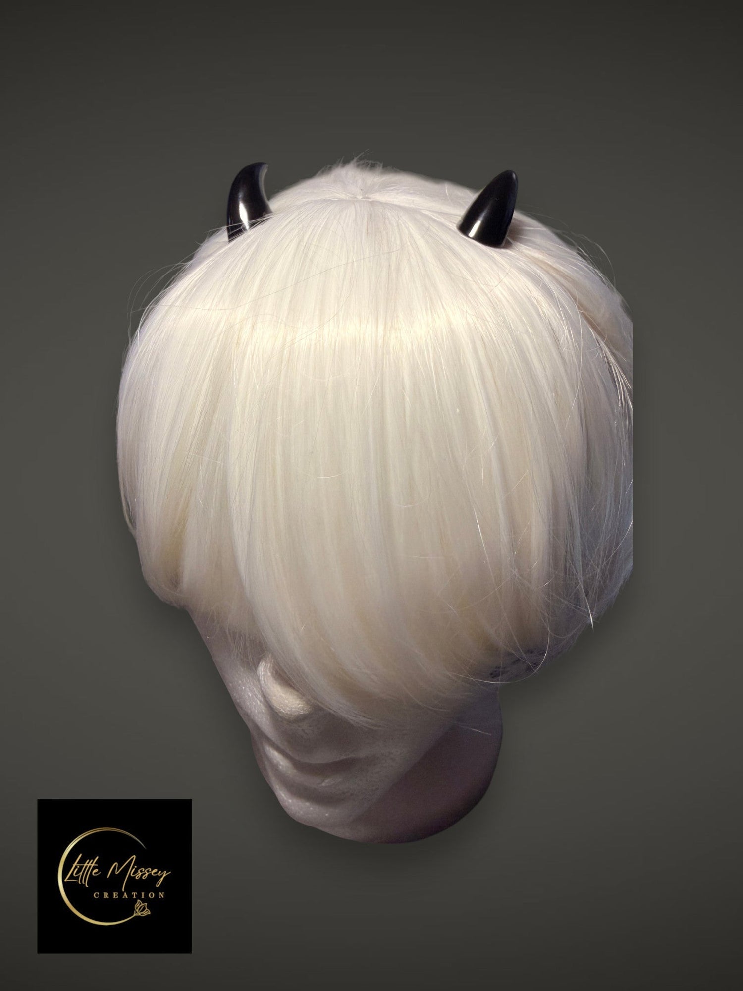 Little Missey Creation black glossy demon horns styled on a short white wig for cosplay and fantasy character looks.
