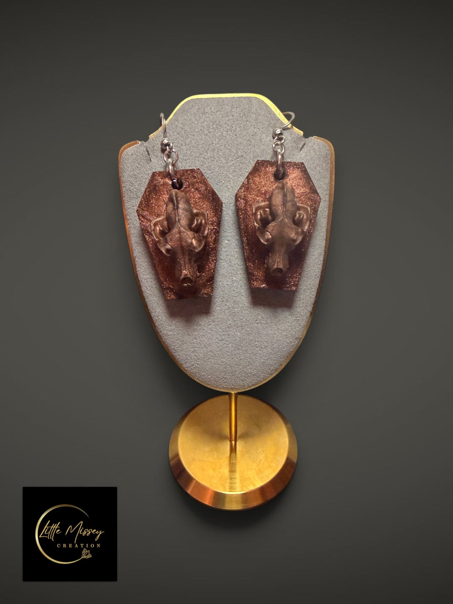 Wolf skull dangle earrings featuring bronze-toned skulls on glittery coffin-shaped bases.