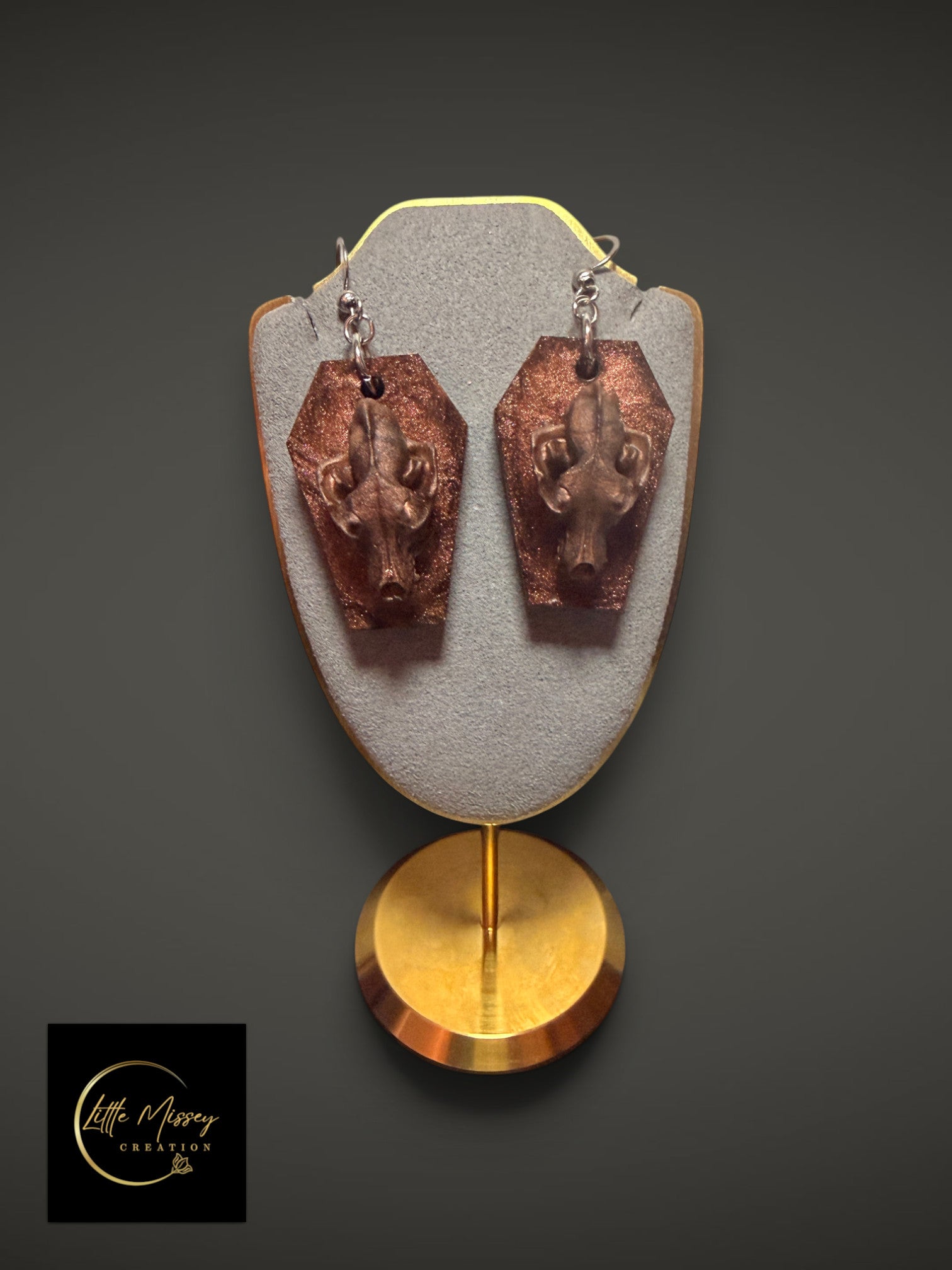 Wolf skull dangle earrings featuring bronze-toned skulls on glittery coffin-shaped bases.