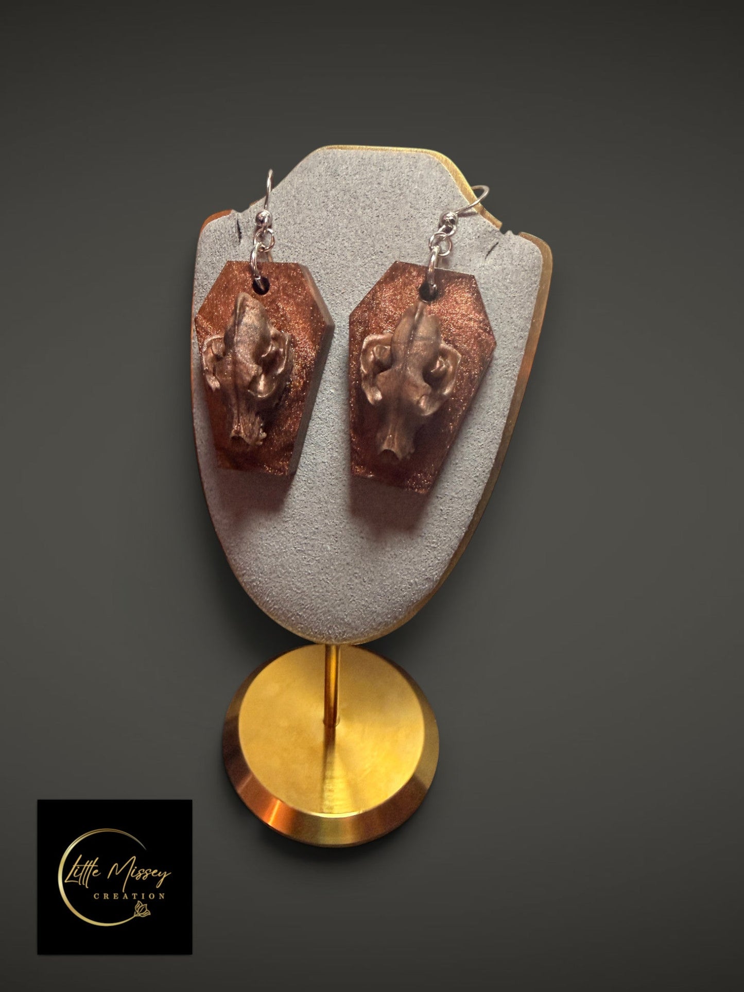 Wolf skull dangle earrings featuring bronze-toned skulls on glittery coffin-shaped bases.