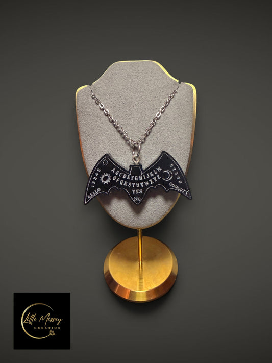 Little Missey Creation black bat-shaped Ouija board pendant necklace on a grey display stand