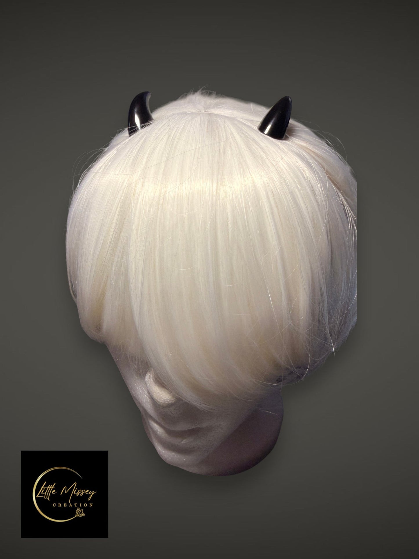 Little Missey Creation black glossy demon horns styled on a short white wig for cosplay and fantasy character looks.