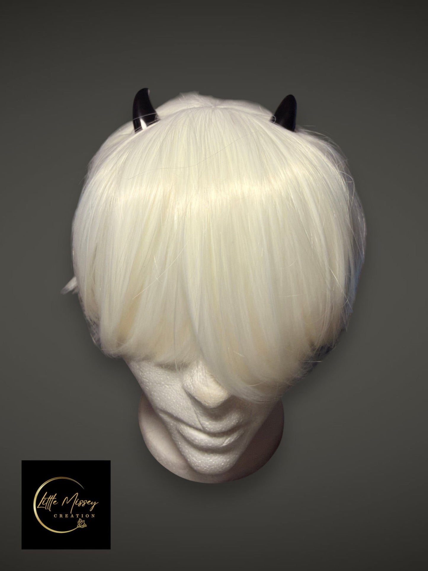 Little Missey Creation black glossy demon horns attached to a short white cosplay wig on a mannequin head