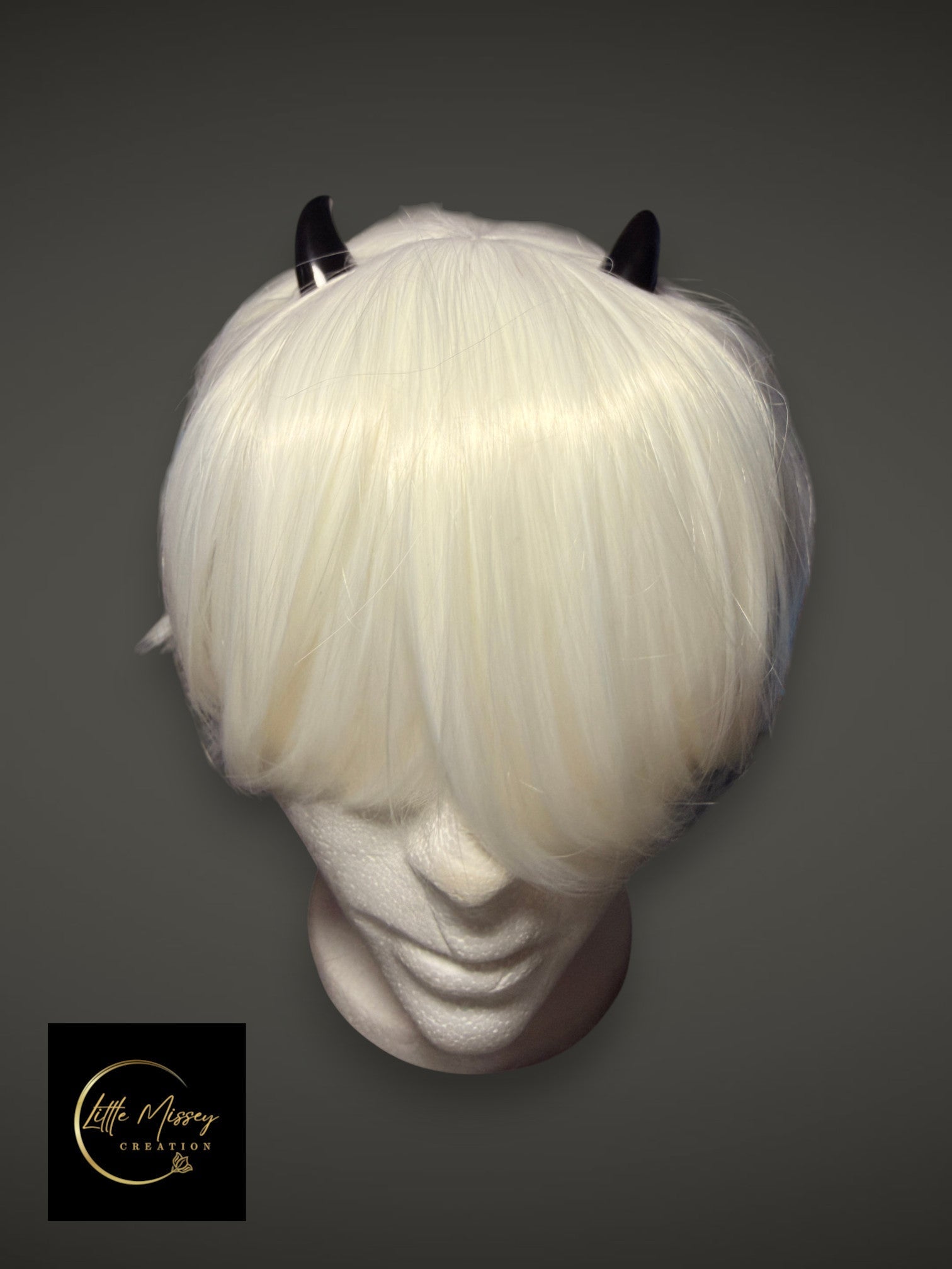 Little Missey Creation black glossy demon horns attached to a short white cosplay wig on a mannequin head