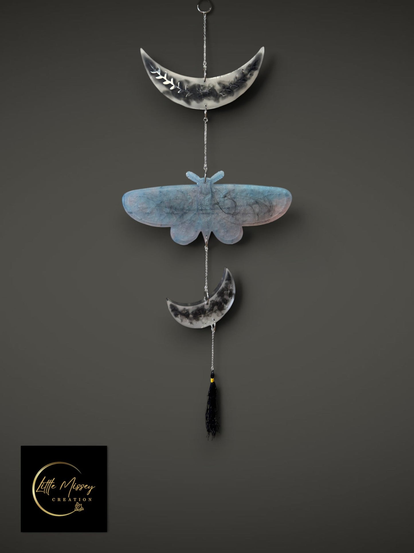 Little Missey Creation celestial moth wall hanging with crescent moons, resin art, and a black tassel on gold chains.