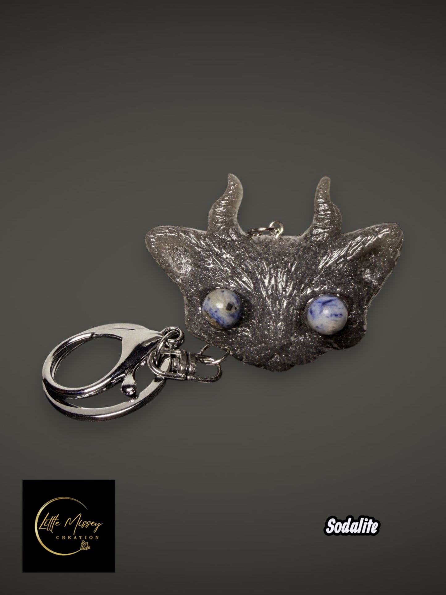 Little Missey Creation fantasy creature keychain with a dark glittery finish and round blue sodalite gemstone eyes.