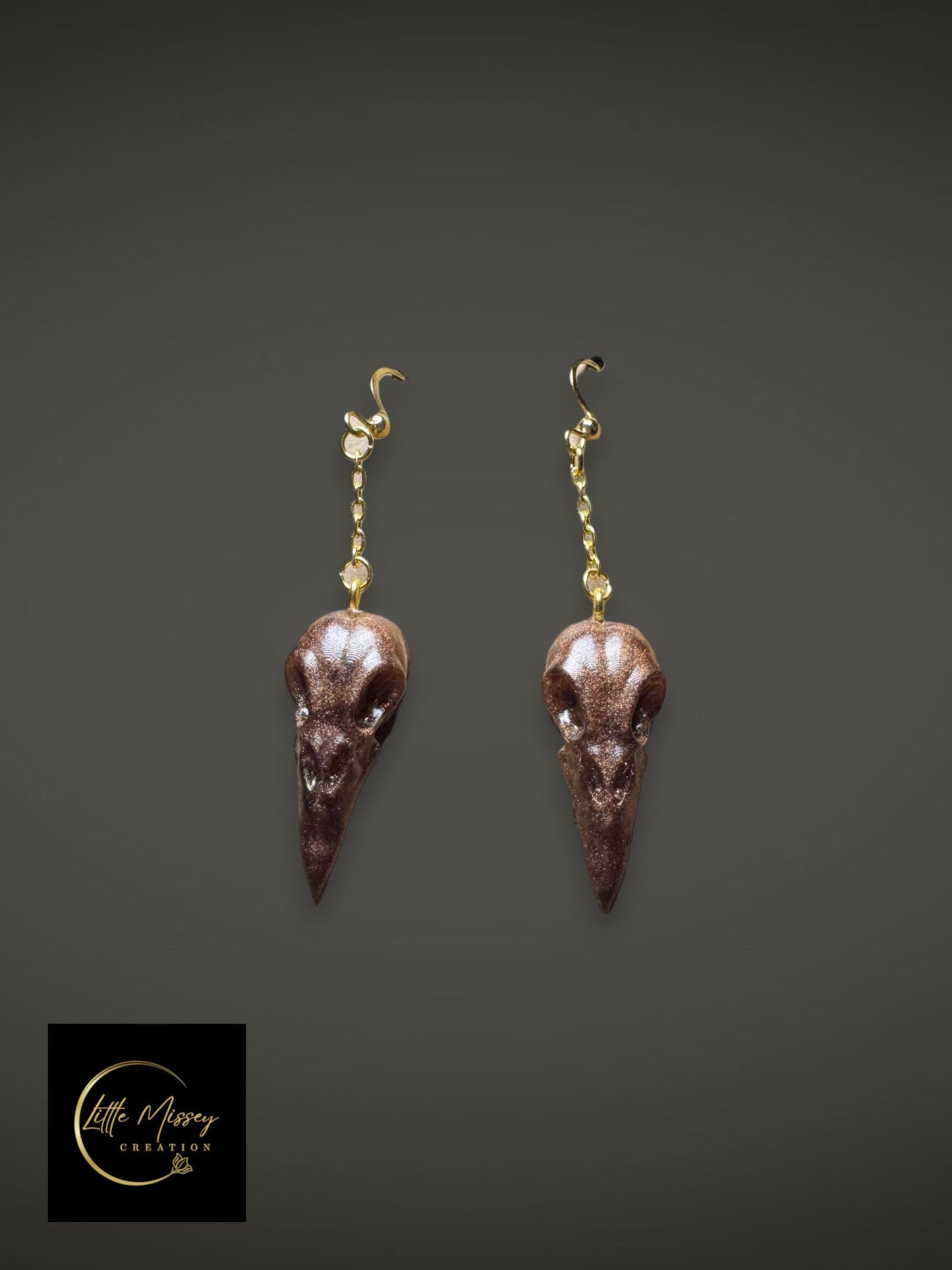 Raven skull earrings in shimmering dark brown resin with gold-toned hardware for gothic style.