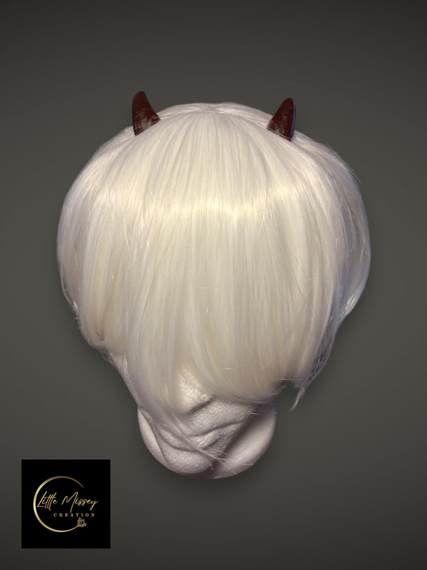 Little Missey Creation dark red glossy demon horns attached to a short white cosplay wig on a mannequin head